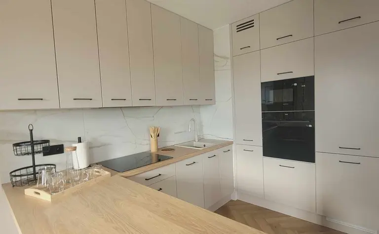 Kuchnia nowoczesna z jasnymi meblami i drewnianym blatem, minimalistyczny design.