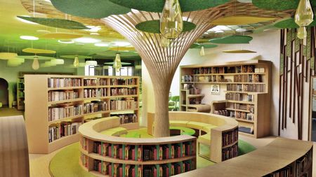 Współczesna biblioteka z drewnianymi regałami i zielonymi detalami