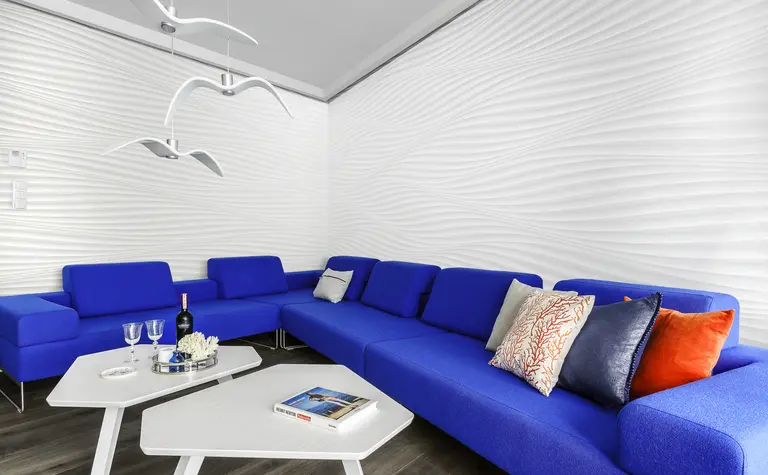 Nowoczesny salon w stylu skandynawskim z niebieską sofą i białą ścianą.