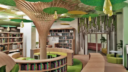 Wnętrze biblioteki z drzewem, zielonymi akcentami i półkami.