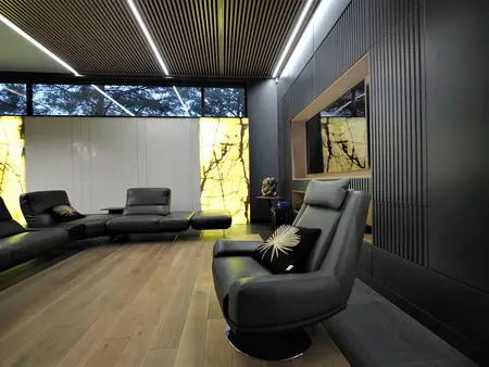 Nowoczesny salon z czarnymi meblami i drewnianą podłogą, z dużymi oknami.