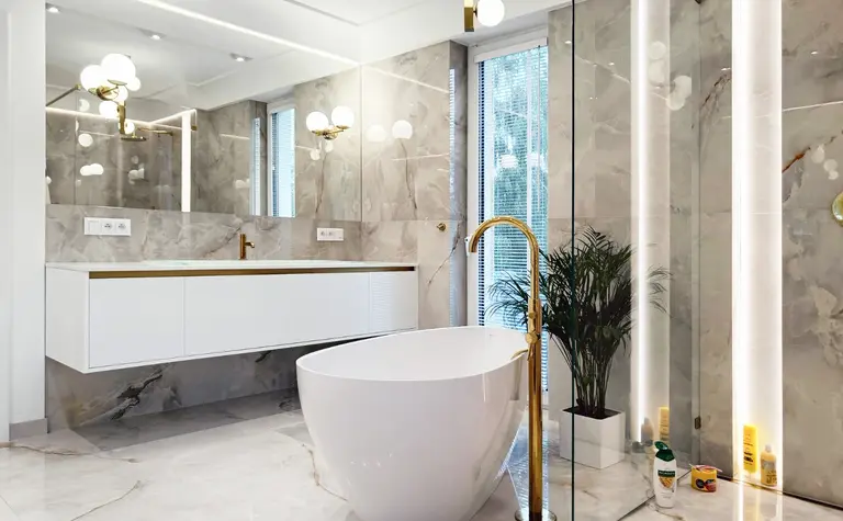 Nowoczesna łazienka glamour z białą wanną i złotymi detalami.