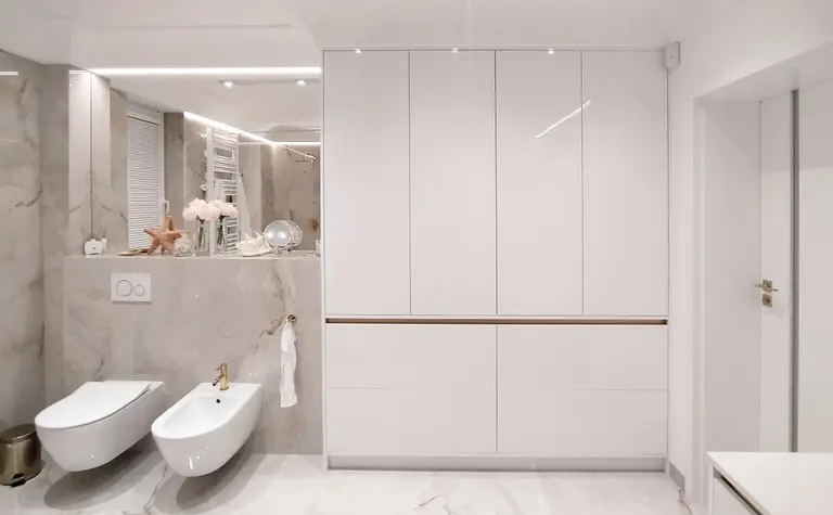 Nowoczesna łazienka glamour z białymi meblami i złotymi detalami.