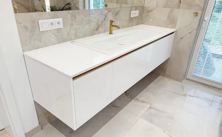 Nowoczesna łazienka z białą umywalką i złotymi detalami w stylu glamour.