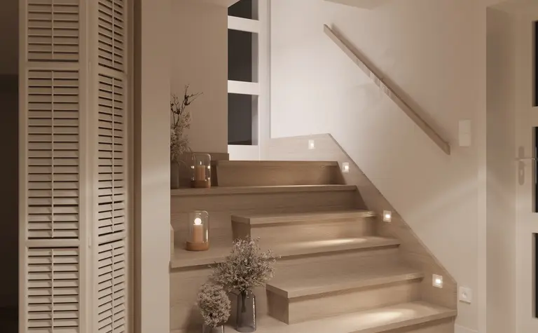 Minimalistyczna klatka schodowa z drewnianymi schodami i dekoracjami.