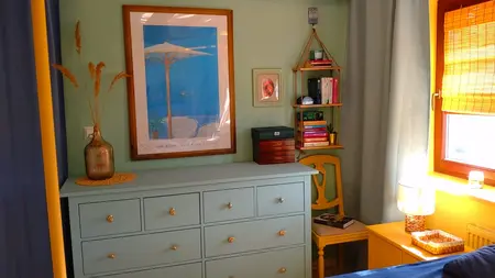 Wnętrze pokoju z boho akcentami, rustykalnym komodą i eklektycznymi detalami.