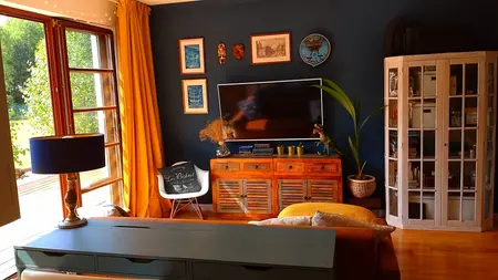 Wnętrze salonu z telewizorem, drewnianymi meblami i eklektycznymi dekoracjami.