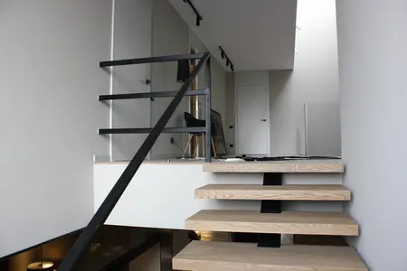 Widok wnętrza z minimalistycznymi schodami i szarymi ścianami, styl minimalistyczny, minimaluxe, nowoczesny.
