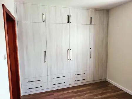 Wnętrze pokoju z tradycyjną białą szafą i drewnianą podłogą.