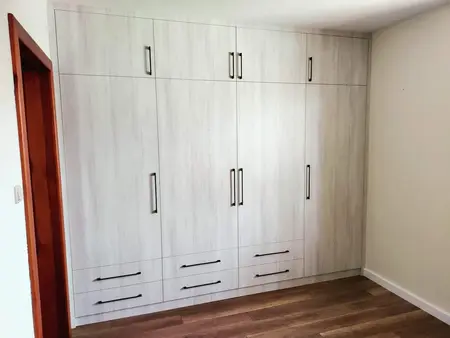Wnętrze pokoju z tradycyjną białą szafą i drewnianą podłogą.