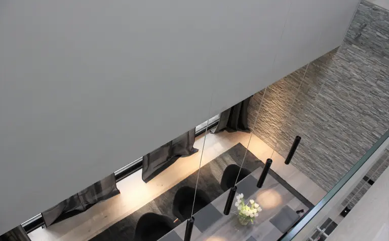 Wnętrze jadalni w stylu minimalistycznym z szarymi ścianami i drewnianym stołem, nowoczesne lampy.