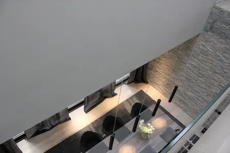 Wnętrze jadalni w stylu minimalistycznym z szarymi ścianami i drewnianym stołem, nowoczesne lampy.
