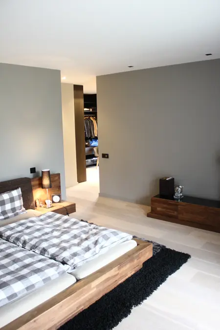 Sypialnia minimalistyczna z drewnianym łóżkiem, szarymi ścianami i nowoczesnymi detalami.