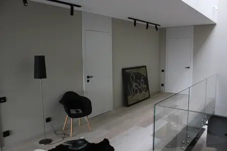 Minimalistyczne wnętrze z czarnym fotelem i dużą grafiką na ścianie, styl minimaluxe.