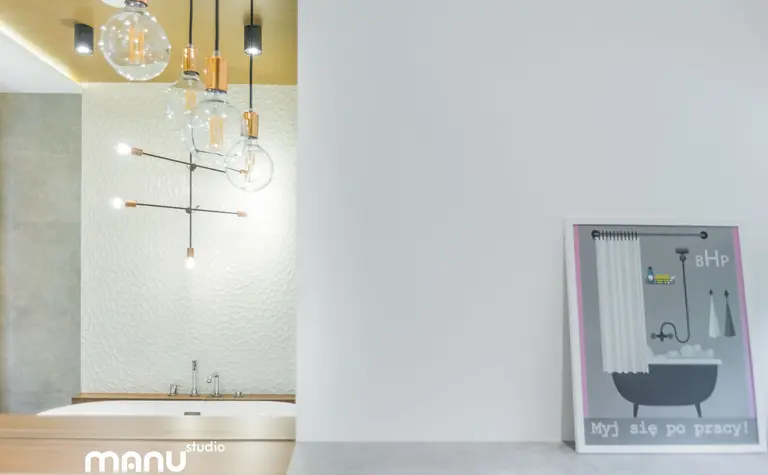 Nowoczesna łazienka z wanną, industrialnym oświetleniem i minimalistycznym wnętrzem.