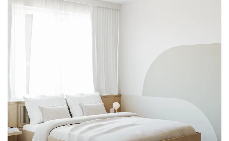 Wnętrze sypialni w stylu japandi z minimalistycznym łóżkiem i nowoczesnymi detalami.