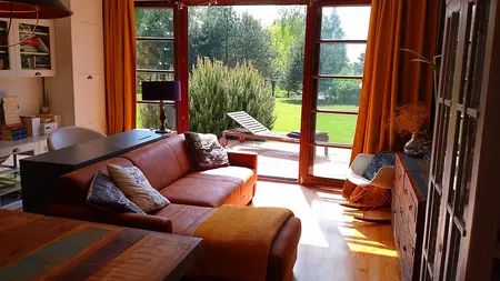 Wnętrze salonu z brązową sofą i dużymi oknami, w stylu boho i skandynawskim.