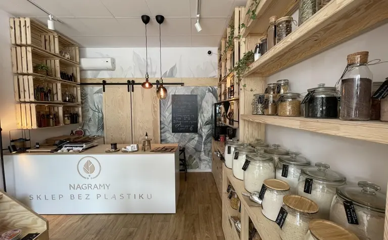 Wnętrze sklepu bez plastiku z drewnianymi półkami i słoikami na produkty sypkie, styl boho.
