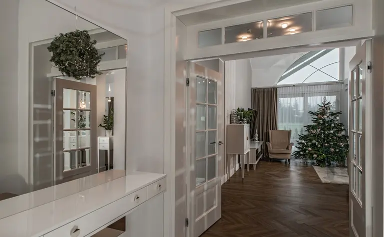 Przedpokój z białymi meblami, drewnianą podłogą i choinką. Styl nowoczesny, quiet luxury, tradycyjny.