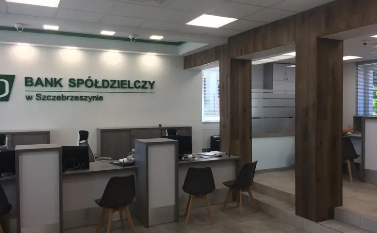 Wnętrze banku z szarymi meblami i drewnianymi detalami, tradycyjny styl.