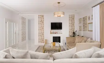 Wnętrze salonu w stylu glamour i quiet luxury z beżową sofą i ozdobnymi ścianami.