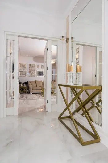 Przedpokój z lustrem, złotą konsolą i designerskim oświetleniem w stylu glamour oraz quiet luxury.