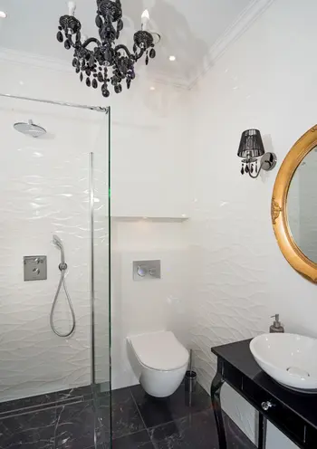 Nowoczesna łazienka z czarnym żyrandolem, białymi płytkami i eleganckimi dodatkami w stylu glamour.