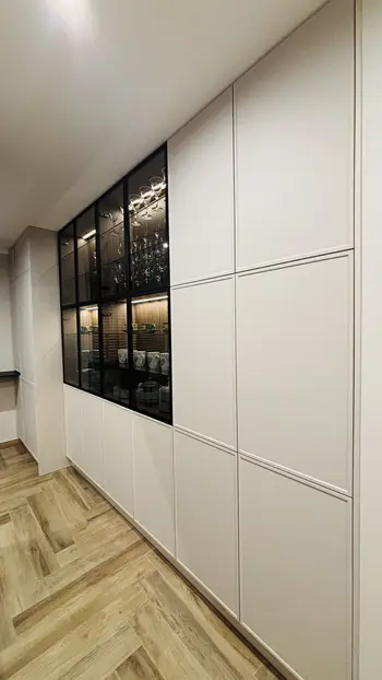 Wnętrze kuchni w stylu industrialnym z białymi meblami i drewnianą podłogą.