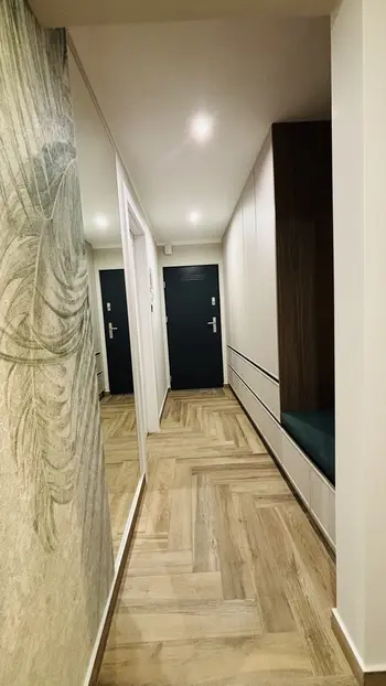 Przedpokój w stylu industrialnym i minimalistycznym z drewnianą podłogą i szafkami.