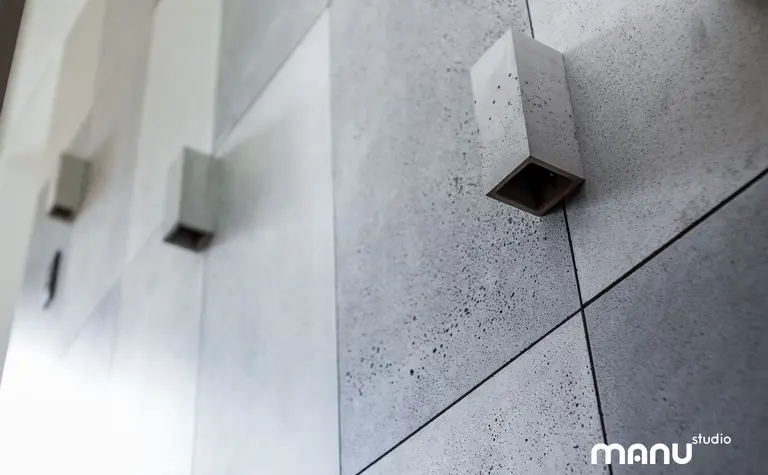 Betonowa ściana z minimalistycznym oświetleniem w industrialnym wnętrzu.
