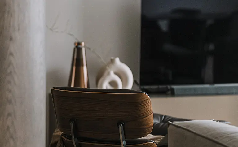 Wnętrze salonu z brązowym fotelem, telewizorem i dekoracjami w stylach minimaluxe, nowoczesnym, quiet luxury, współczesnym.