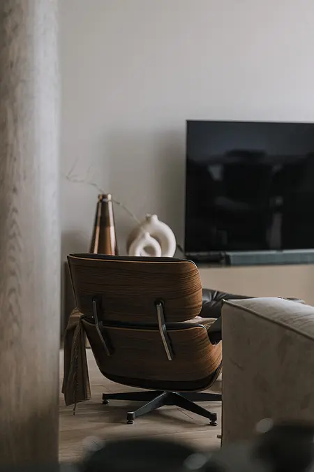 Wnętrze salonu z brązowym fotelem, telewizorem i dekoracjami w stylach minimaluxe, nowoczesnym, quiet luxury, współczesnym.