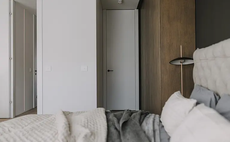 Wnętrze sypialni z minimalistycznym designem, nowoczesnymi elementami i drewnianymi akcentami.