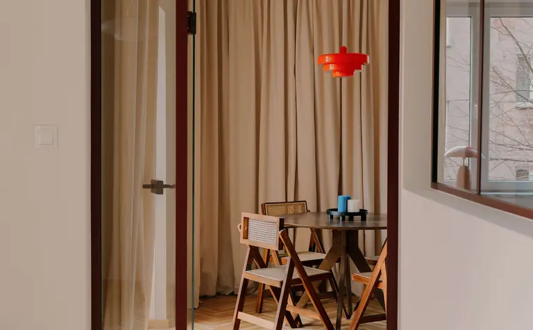 Wnętrze jadalni w stylu quiet luxury z drewnianym stołem i vintage lampą.