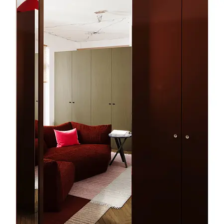 Garderoba w stylu eklektycznym z czerwoną kanapą i zielonymi szafkami, minimalistyczne detale.