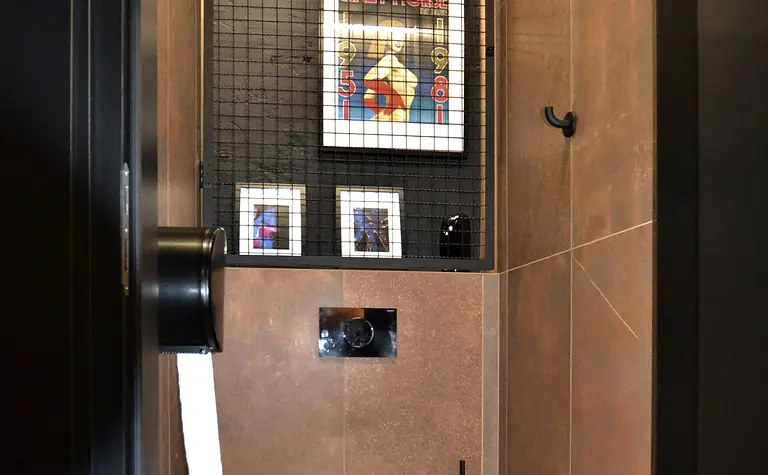 Toaleta z brązowymi płytkami, czarnym WC i nowoczesnymi detalami