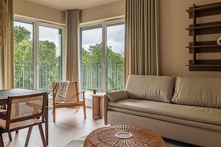 Wnętrze salonu w stylu boho i japandi z beżową sofą i drewnianymi elementami.
