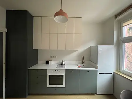 Kuchnia w stylu industrialnym i minimalistycznym z białymi i zielonymi meblami