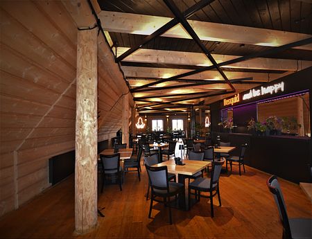 Wnętrze restauracji z drewnianymi elementami i nowoczesnym oświetleniem, industrialny styl.