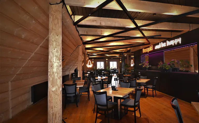 Wnętrze restauracji z drewnianymi elementami i nowoczesnym oświetleniem, industrialny styl.