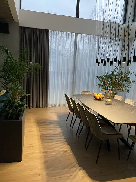 Jadalnia z dużym stołem, roślinami i oknami w stylu nowoczesnym.