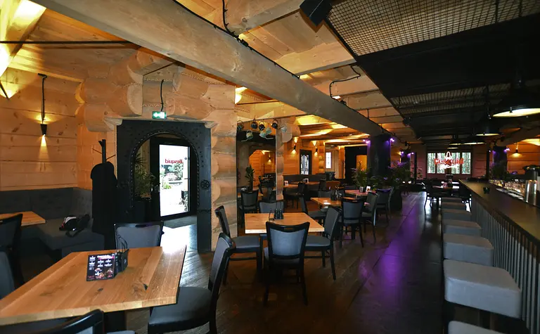 Wnętrze restauracji z drewnianymi akcentami i nowoczesnym wystrojem, industrialny styl.