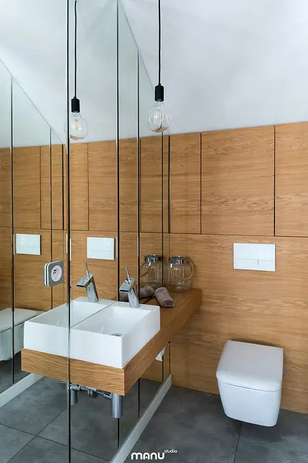 Nowoczesna łazienka z drewnianymi meblami i lustrami w stylu industrialnym i minimalistycznym.
