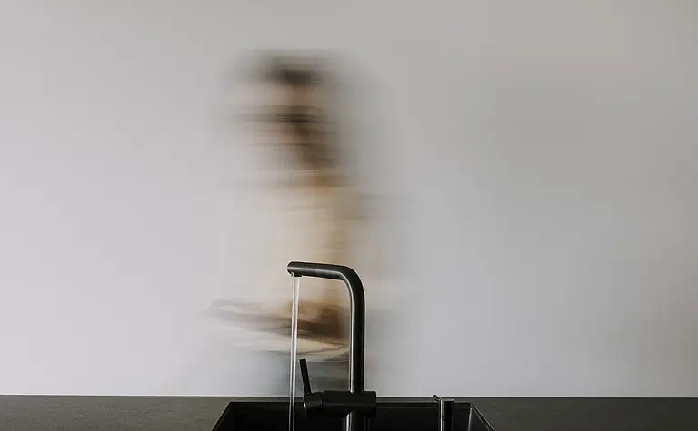 Wnętrze kuchni z czarnym blatem, minimalistycznym designem i nowoczesnym oświetleniem.
