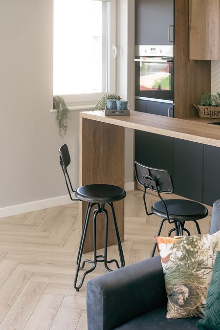 Kuchnia z industrialnym akcentem, drewniany stół i czarne krzesła