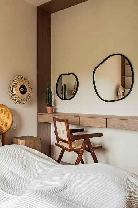 Sypialnia w stylu boho z rustykalnym drewnem, minimalistycznym biurkiem i lustrami.