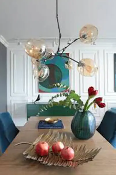 Jadalnia z minimalistycznym wystrojem, lampa i kwiaty w wazonie w stylu quiet luxury.