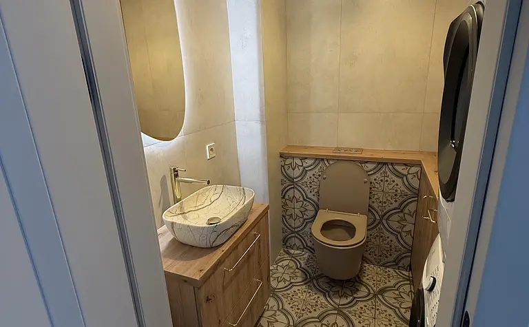 Nowoczesna łazienka w stylu boho z drewnianą szafką i dekoracyjną podłogą.