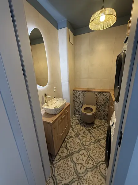 Nowoczesna łazienka w stylu boho z drewnianą szafką i dekoracyjną podłogą.