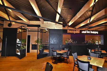 Wnętrze restauracji z industrialnym stylem, drewnianymi elementami i roślinami.